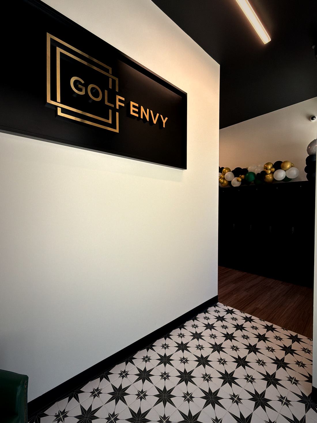 The gold Golf Envy sign in the club lobby above star-pattern tile